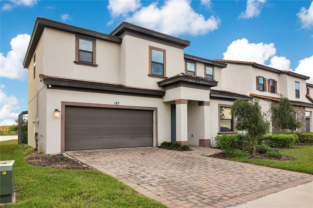 A two-story house with a beige stucco exterior, a two-car garage, and a paved driveway — 183 MITCHELLS MANOR, HAINES CITY, FL