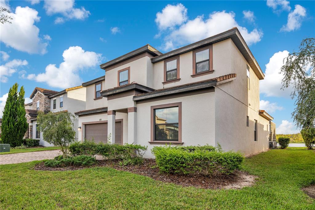 A two-story suburban house with a stucco exterior, a two-car garage, and a grassy yard — 183 MITCHELLS MANOR, HAINES CITY, FL