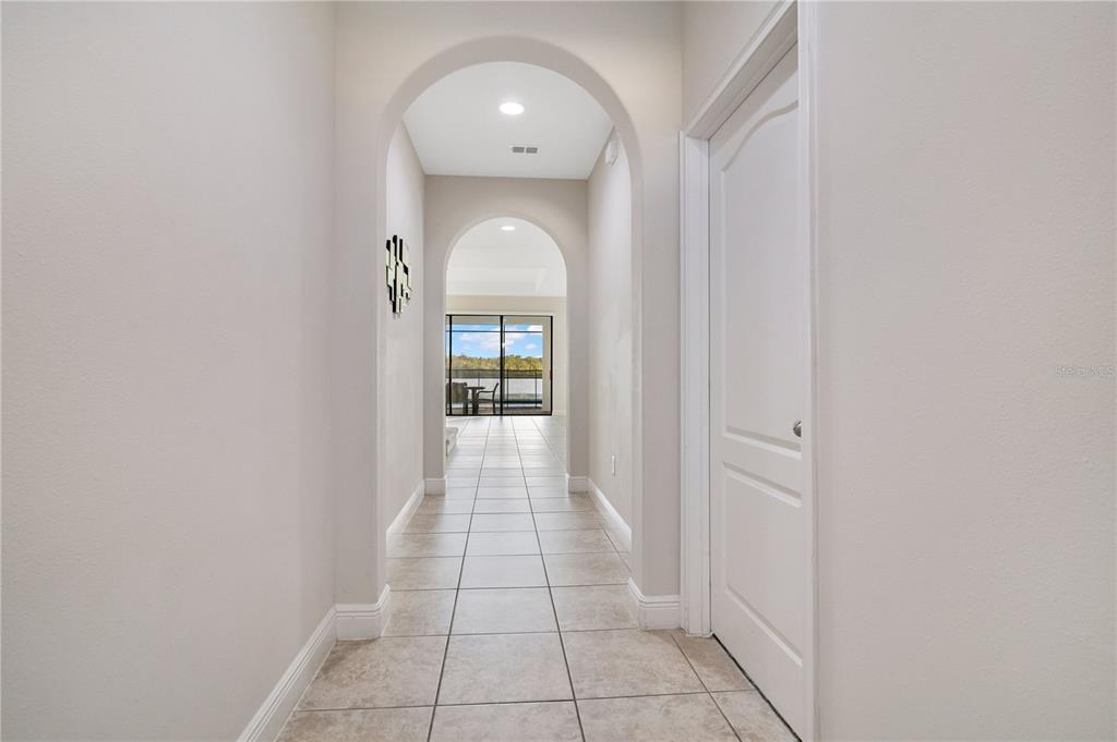 A tiled hallway with arched openings leads to a view of a lake — 183 MITCHELLS MANOR, HAINES CITY, FL
