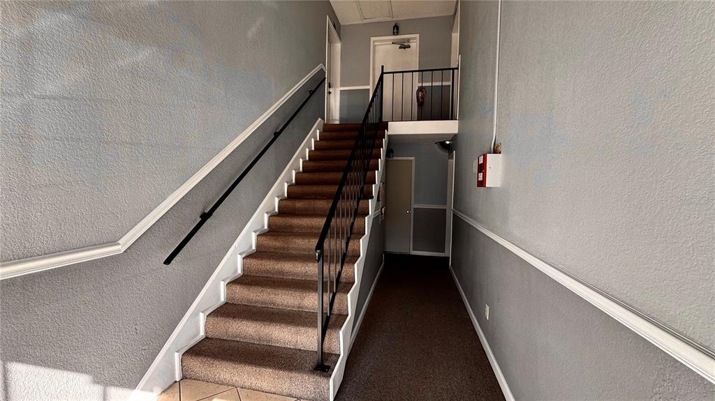 A carpeted staircase with a black metal railing leads to an upper landing — 205 LEWFIELD CIRCLE UNIT 205, WINTER PARK, FL