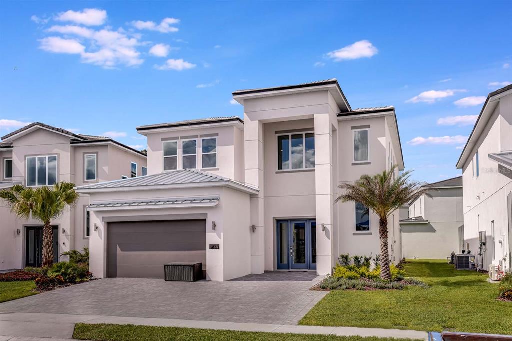 A two-story modern house with a gray garage, blue front doors, and a paved driveway — 2133 PINE OAK LOOP, DAVENPORT, FL