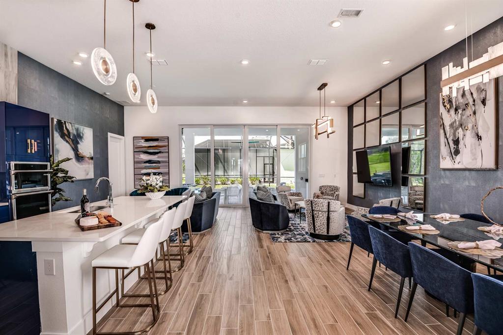 An open-concept kitchen, dining, and living area with modern furniture, dark blue walls, and tile flooring — 2133 PINE OAK LOOP, DAVENPORT, FL