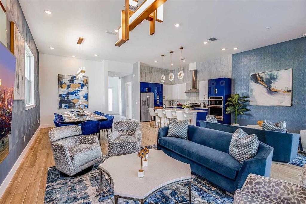 An open-concept living and dining area features blue cabinetry, patterned armchairs, and a large rug — 2133 PINE OAK LOOP, DAVENPORT, FL