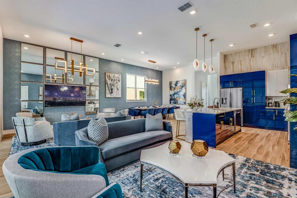 An open-concept living room and kitchen featuring blue cabinetry, a mirrored wall, and modern furniture — 2133 PINE OAK LOOP, DAVENPORT, FL