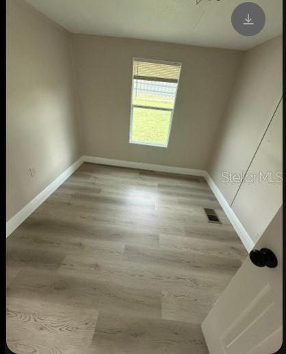A small, empty bedroom features light-colored wood-look flooring, beige walls, and a single window — 14810 THOMPSON AVENUE, HUDSON, FL