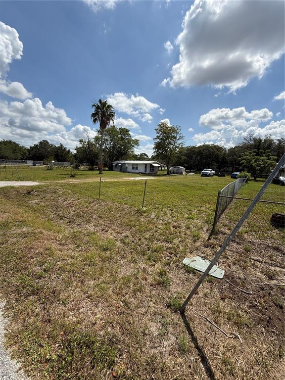 A grassy lot features a small white house in the distance under a cloudy sky — 14810 THOMPSON AVENUE, HUDSON, FL