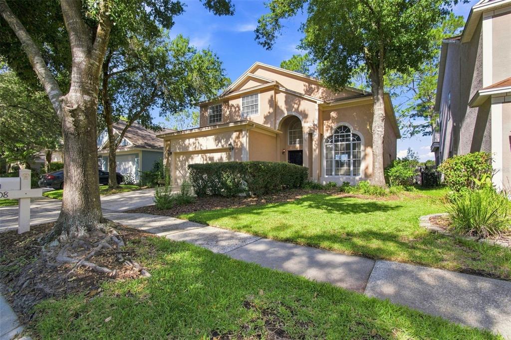 A two-story, tan-colored suburban house features a two-car garage, arched windows, and a front lawn — 17708 LONG RIDGE ROAD, TAMPA, FL