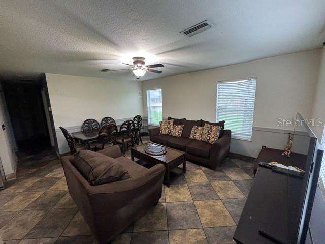 A living room features a brown sofa, a matching armchair, a coffee table, and tile flooring — 14373 IRVING STREET, SPRING HILL, FL