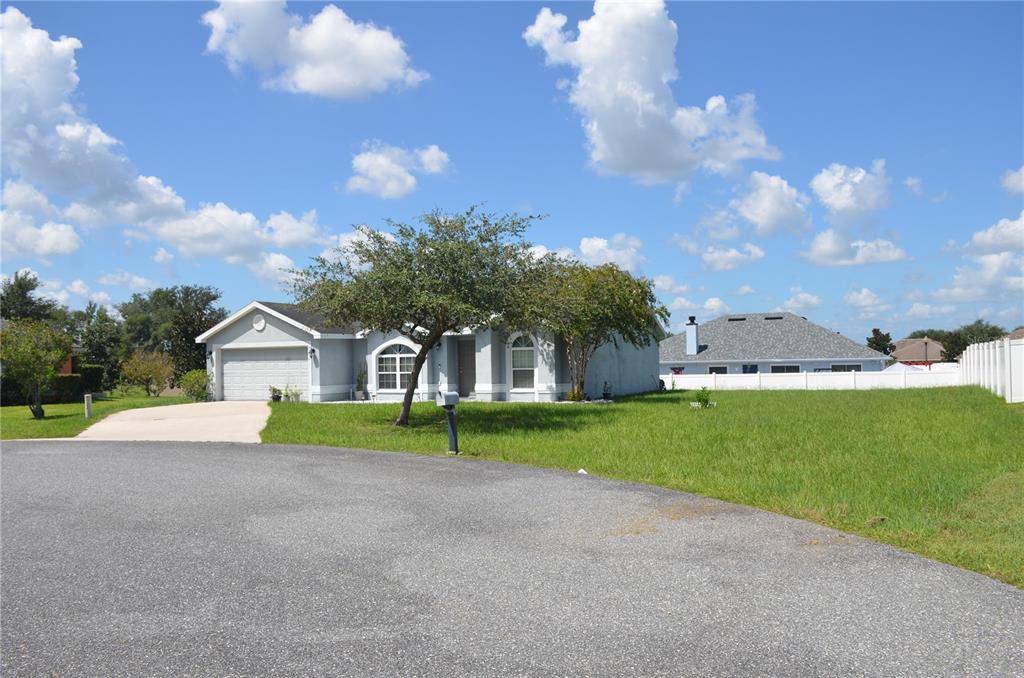 A single-story house with a garage and a large front lawn under a blue sky — 9916 SW 56TH AVENUE, OCALA, FL