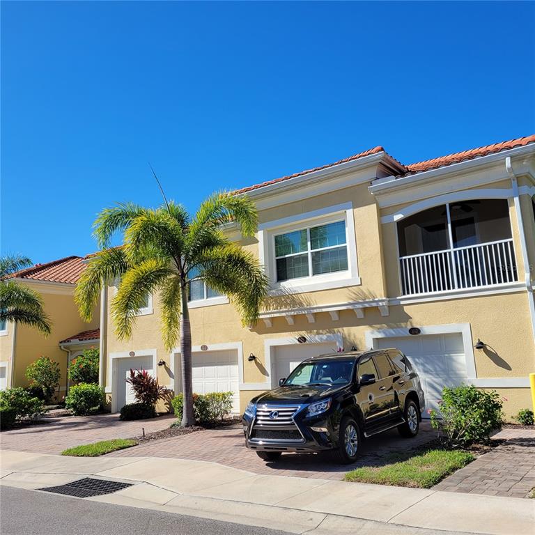 A black SUV is parked in the driveway of a two-story tan townhouse — 152 NAVIGATION CIRCLE UNIT 107, OSPREY, FL