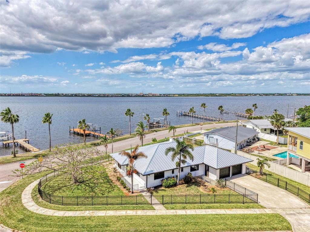 An aerial view shows a white house with a metal roof near a large body — 1822 RIVERSIDE DRIVE E, BRADENTON, FL