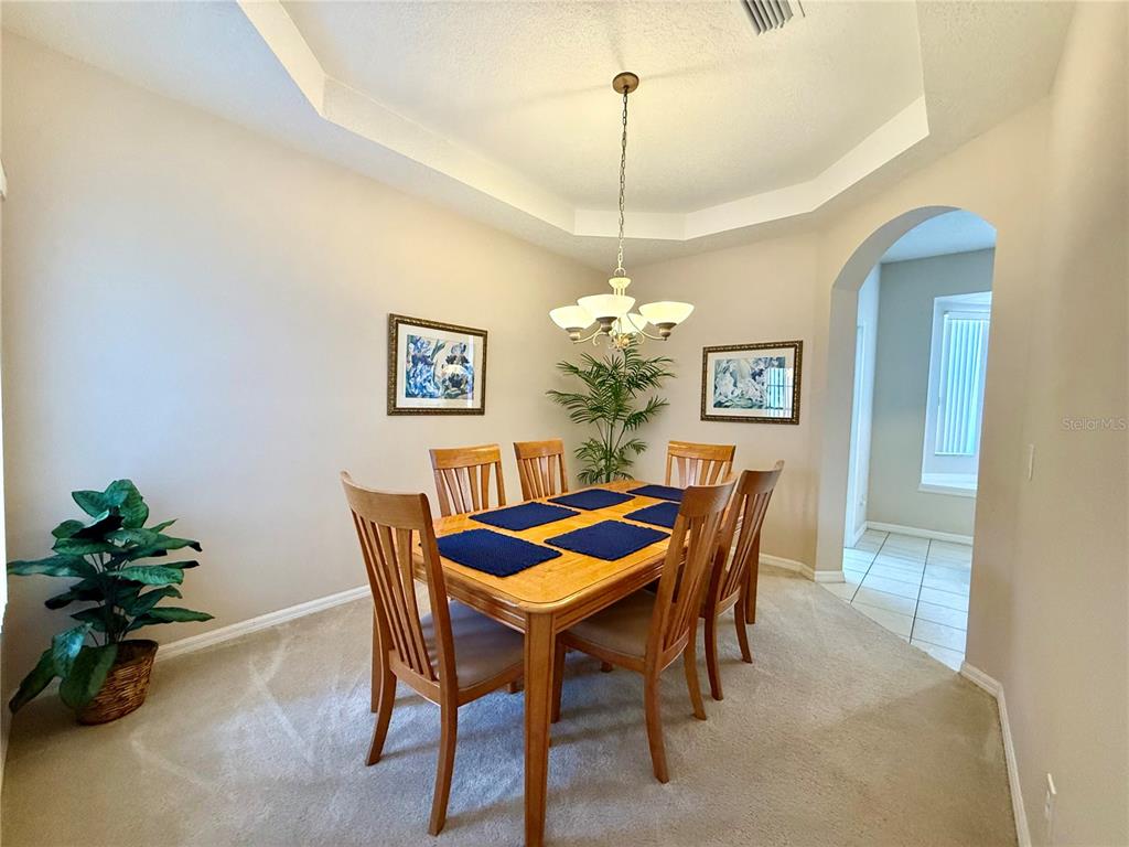 A dining room features a wooden table with six chairs, a chandelier, and carpeted flooring — 113 PLUMOSO LOOP, DAVENPORT, FL