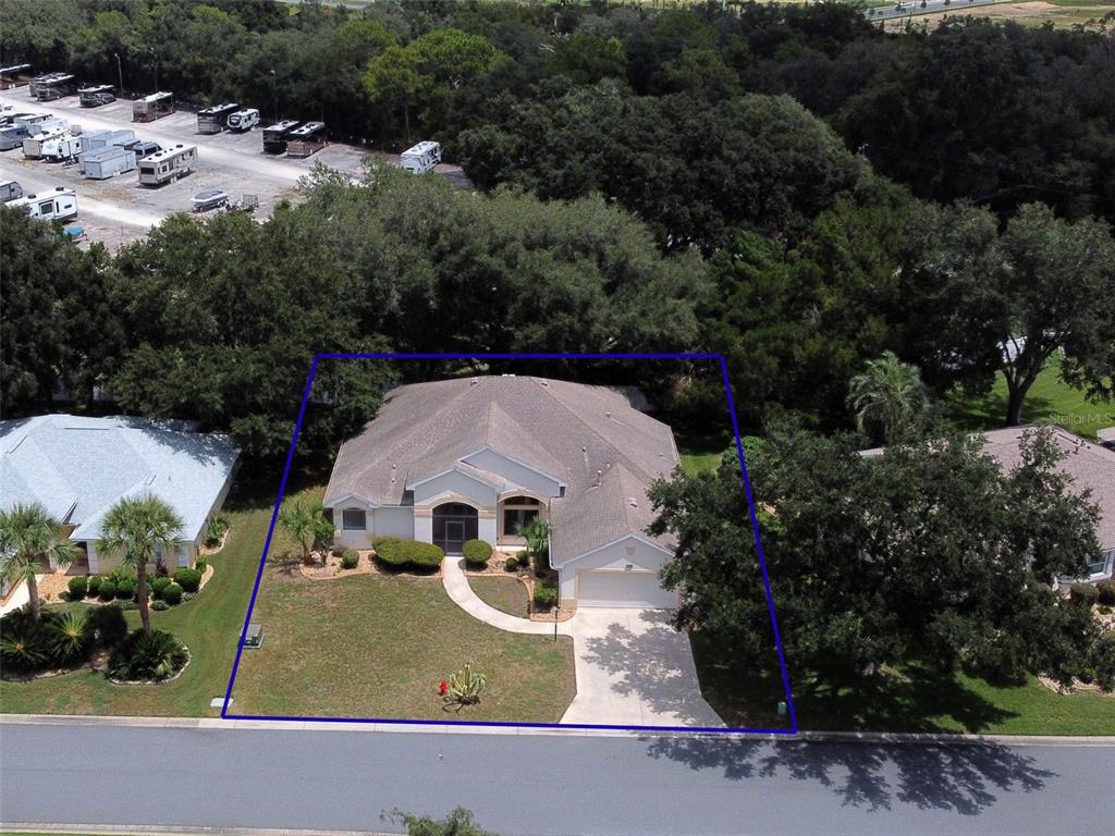 An aerial view shows a single-story house with a driveway and lawn within a blue border — 5925 BAG PIPE PLACE, LEESBURG, FL
