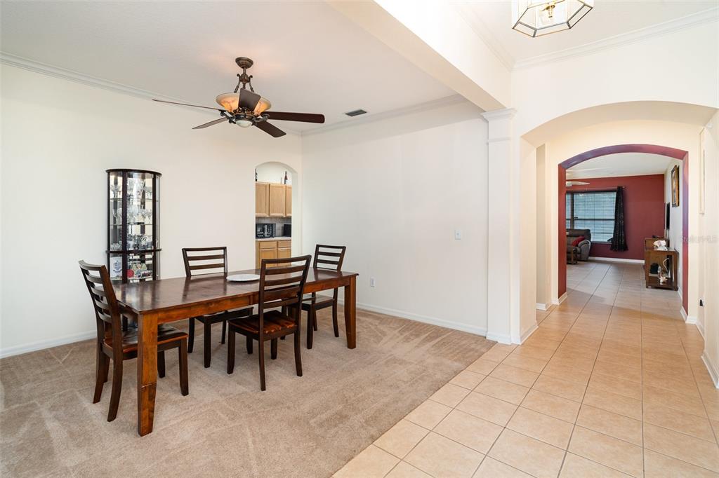 A dining room with a wooden table and chairs sits next to a tiled hallway — 10903 WILDCAT DRIVE, RIVERVIEW, FL
