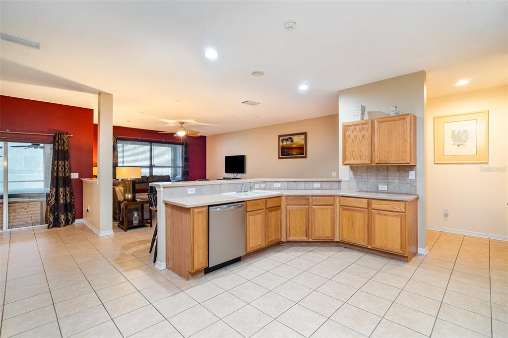 A kitchen with light wood cabinets and tile flooring overlooks a living area — 10903 WILDCAT DRIVE, RIVERVIEW, FL