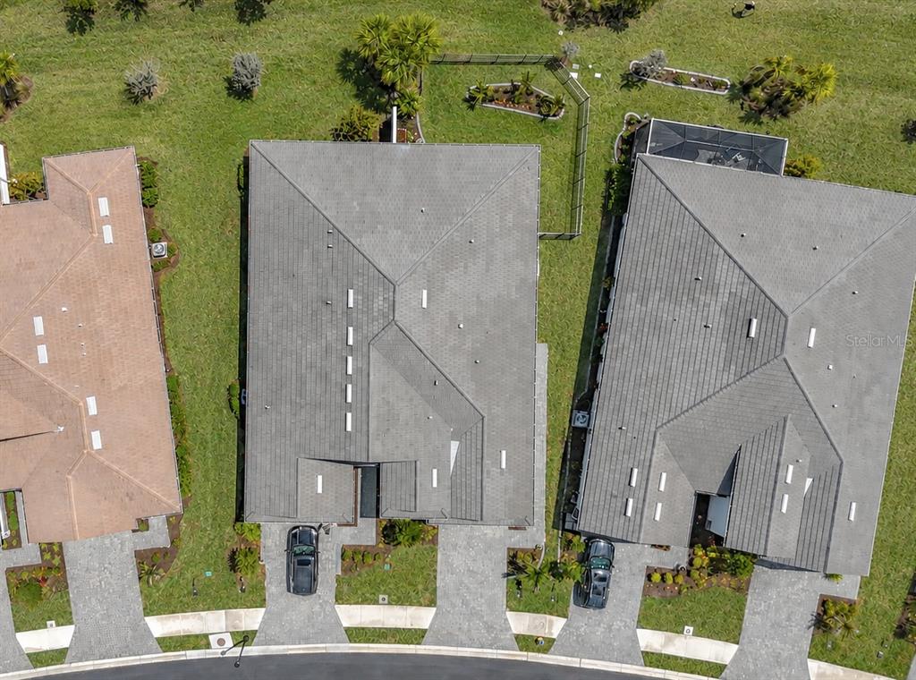 A backyard features a manicured lawn, a curved garden bed, and a black metal fence — 18604 DAYSPRING PLACE, VENICE, FL