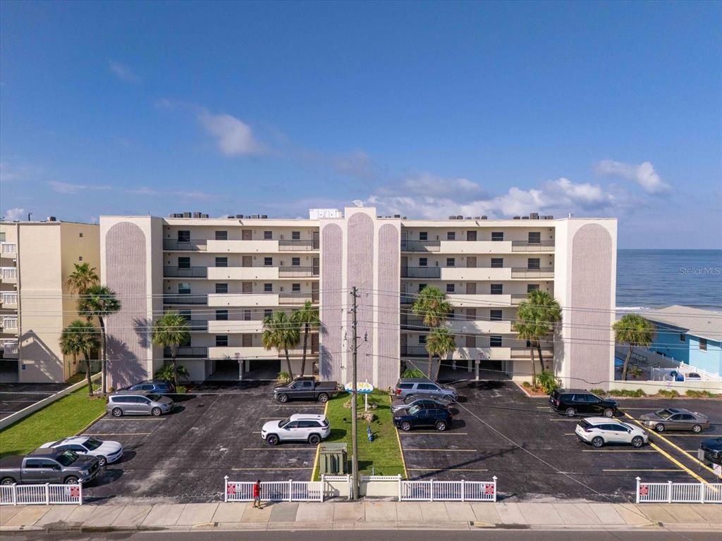 An exterior view of a multi-story apartment building with a parking lot in front — 14300 GULF BOULEVARD UNIT 206, MADEIRA BEACH, FL