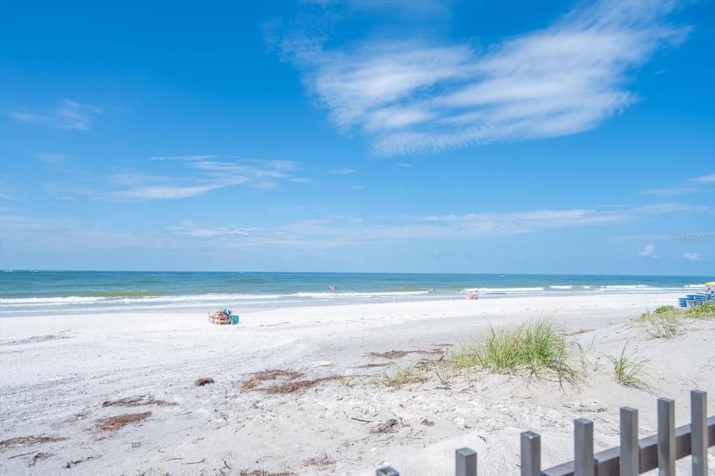A view of a sandy beach with ocean waves under a bright blue sky — 14300 GULF BOULEVARD UNIT 206, MADEIRA BEACH, FL