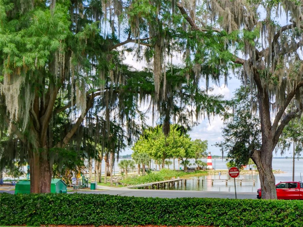 A brick-paved courtyard features a pergola, hanging plants, a small fountain, and a front door — 100 S TREMAIN STREET UNIT G2, MOUNT DORA, FL