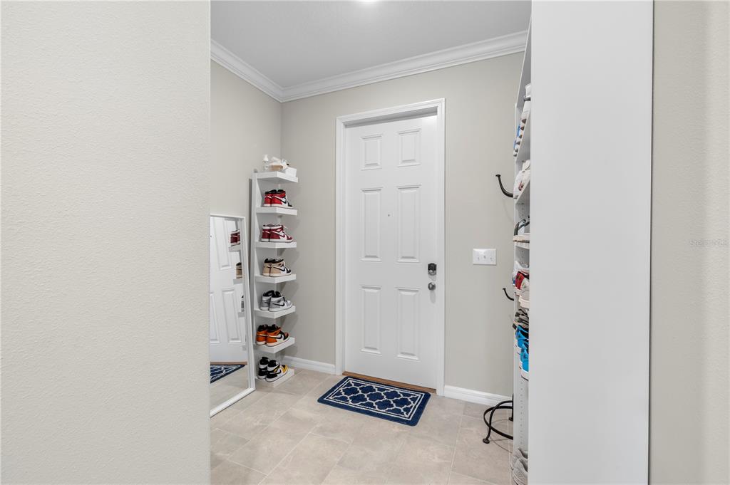 An entryway features a white door, a corner shoe rack, and a tall shelving unit — 31940 BLUE PASSING LOOP, WESLEY CHAPEL, FL