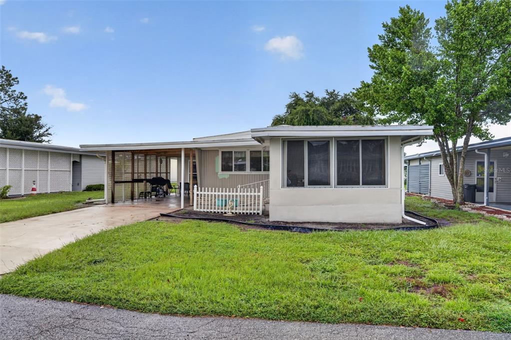 A single-story house with a carport, a white picket fence, and a screened-in front porch — 219 PARADISE S, LEESBURG, FL