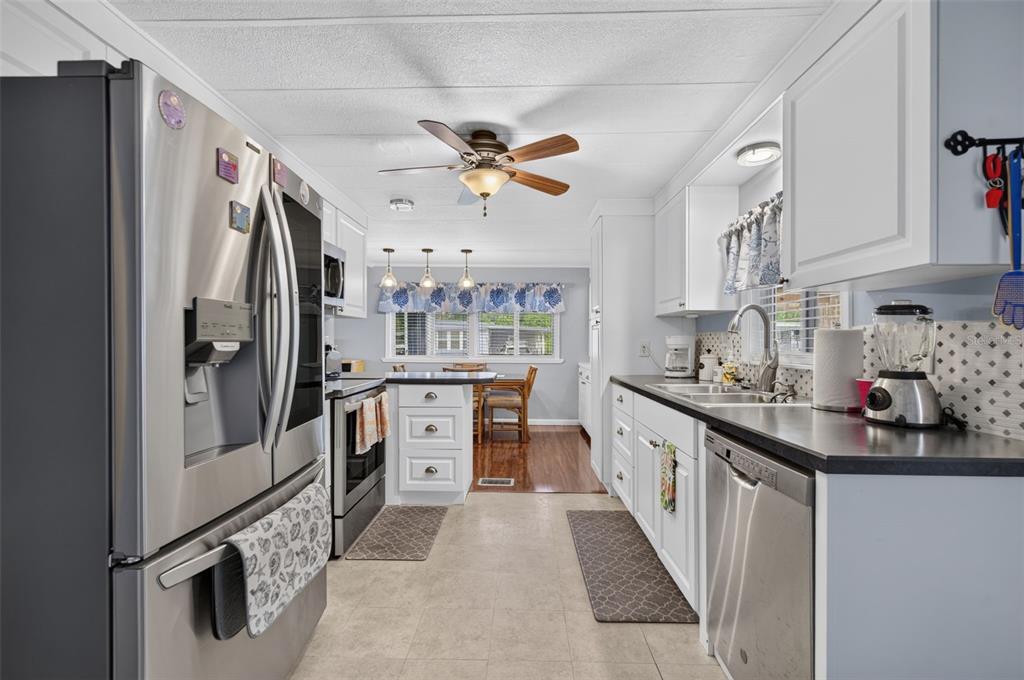 A kitchen with stainless steel appliances, white cabinets, and a view into the dining area — 219 PARADISE S, LEESBURG, FL