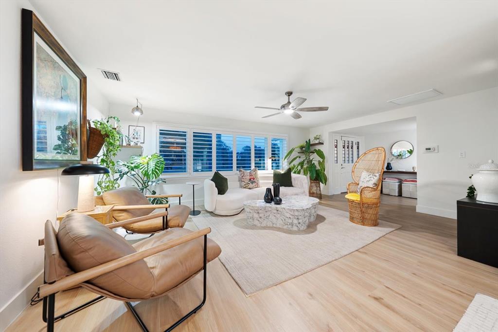 A bright living room features a white curved sofa, two leather chairs, and a marble table — 821 JACARANDA DRIVE, LARGO, FL