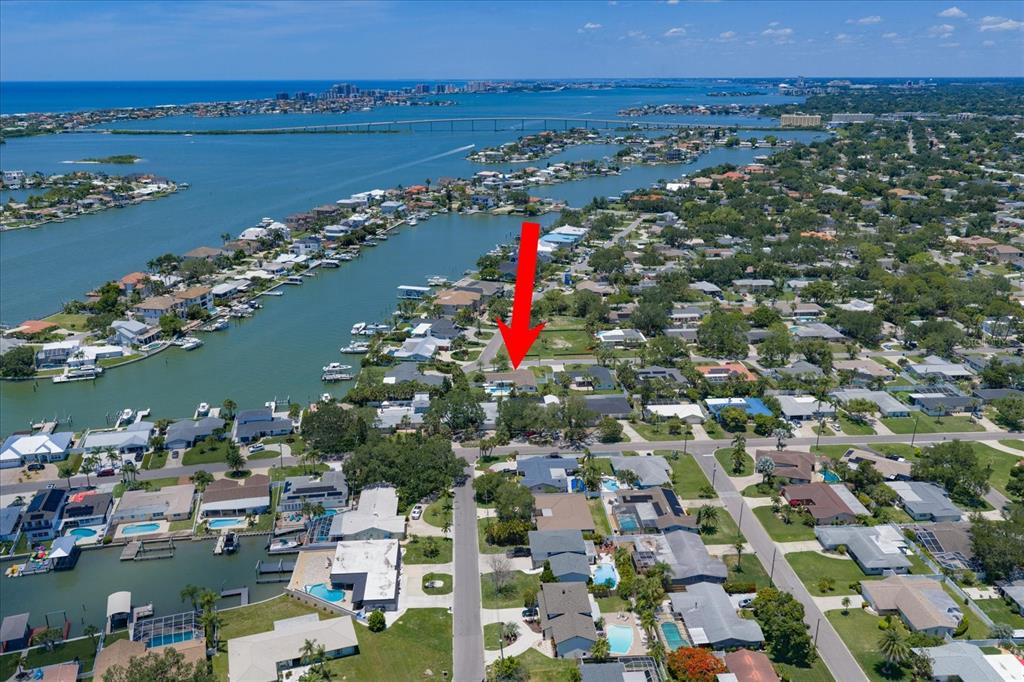 An aerial view of a waterfront residential neighborhood with a red arrow pointing to a house — 821 JACARANDA DRIVE, LARGO, FL