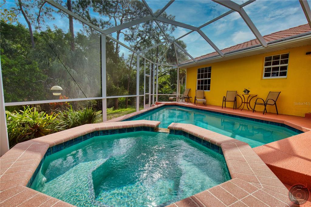 A screened-in patio features a hot tub and swimming pool next to a yellow house — 3471 DATURA ROAD, VENICE, FL