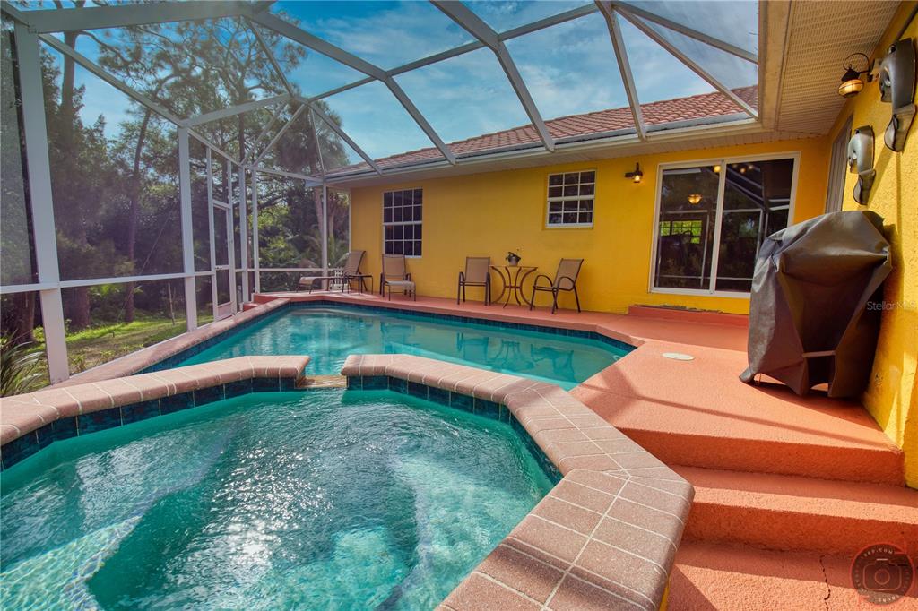 A screened-in patio features a swimming pool, a raised hot tub, and yellow exterior walls — 3471 DATURA ROAD, VENICE, FL