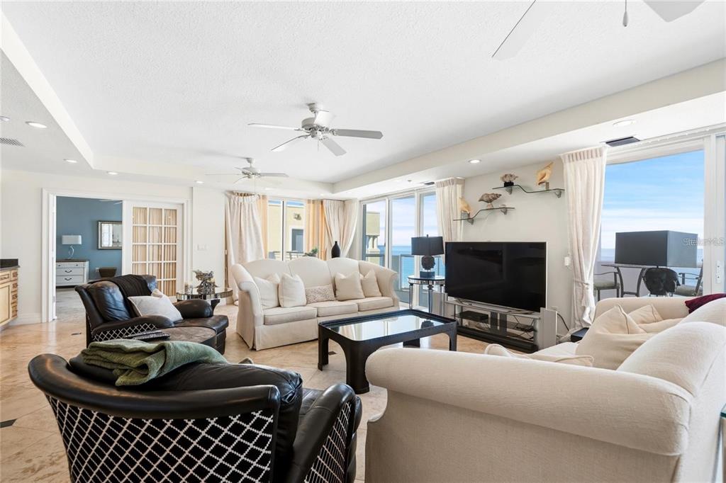 A spacious living room features two white sofas, two leather armchairs, and floor-to-ceiling windows — 1350 GULF BOULEVARD UNIT 901, CLEARWATER BEACH, FL