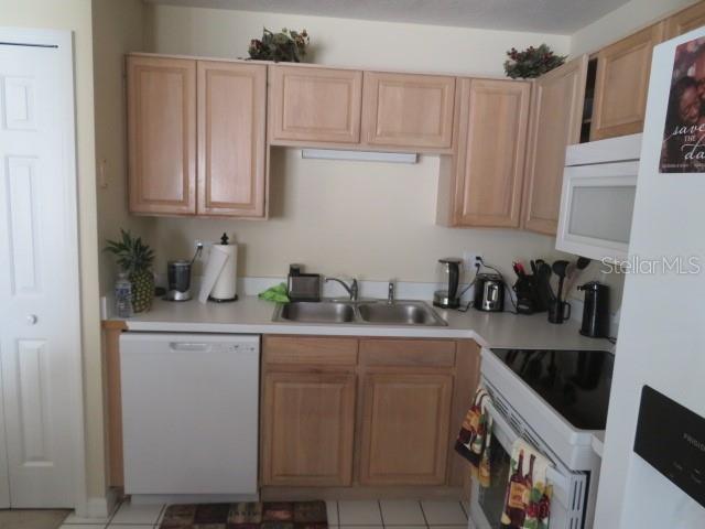 A kitchen features light wood cabinets, a stainless steel sink, and a white dishwasher — 1188 N FAIRWAY DRIVE UNIT 1188, APOPKA, FL