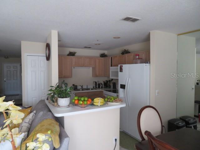 A kitchen with light wood cabinets, a white refrigerator, and a breakfast bar — 1188 N FAIRWAY DRIVE UNIT 1188, APOPKA, FL
