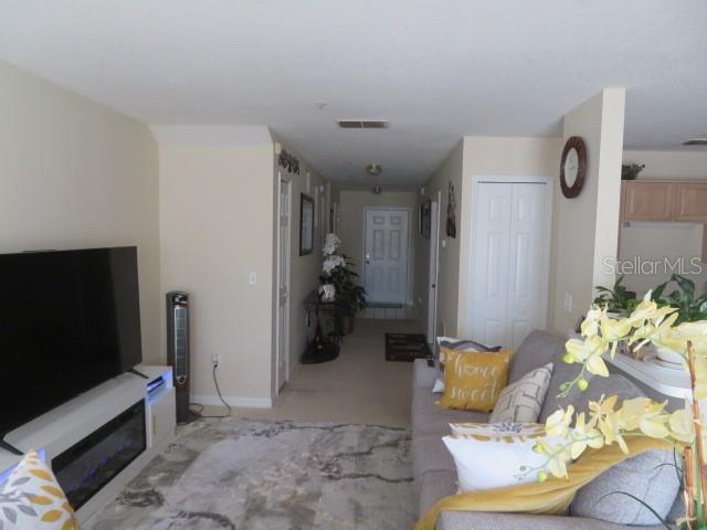 A living room features a television, fireplace console, sofa, and a hallway leading to an entrance — 1188 N FAIRWAY DRIVE UNIT 1188, APOPKA, FL