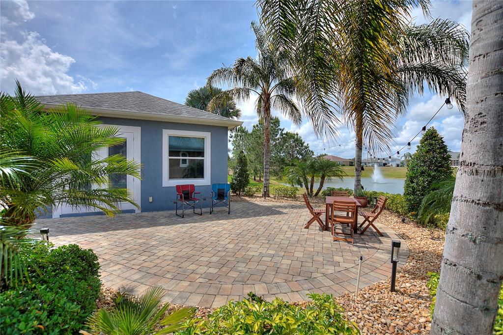A paved patio features outdoor furniture, palm trees, and a view of a pond — 544 NARROW POND ROAD, POLK CITY, FL