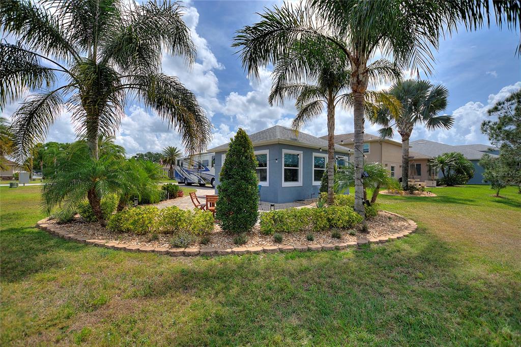 A small blue detached structure sits in a landscaped yard with palm trees and an RV — 544 NARROW POND ROAD, POLK CITY, FL