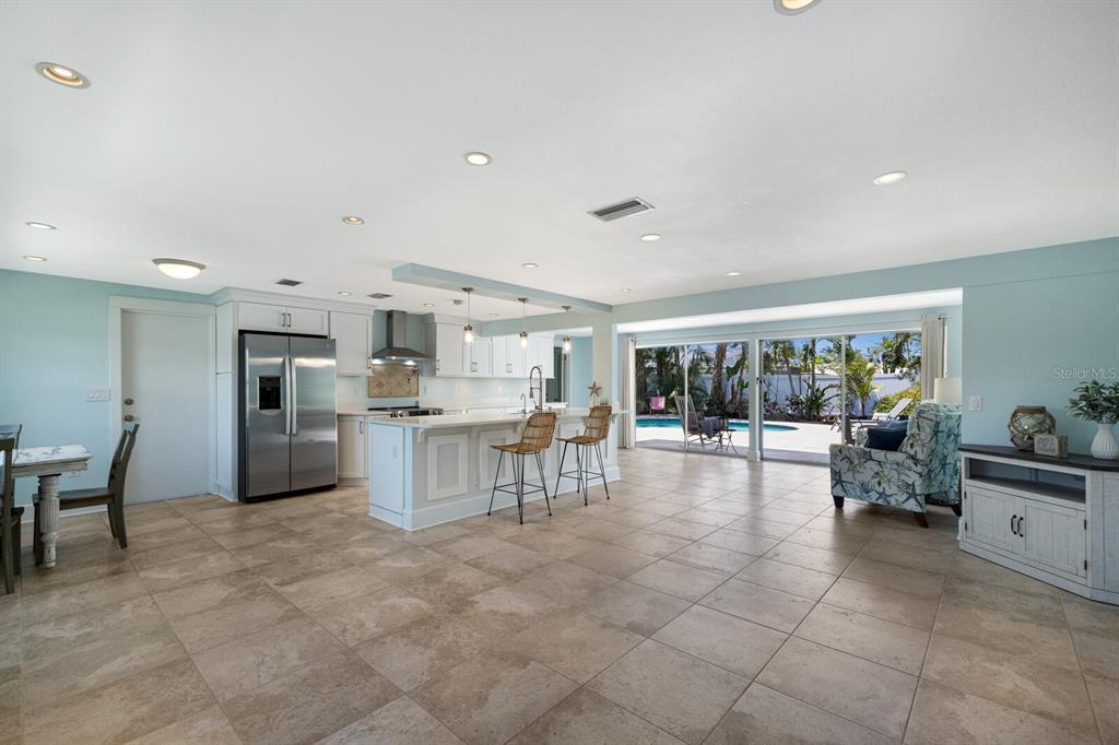An open-concept kitchen and living area features tile flooring, white cabinetry, and sliding glass doors — 506 69TH STREET, HOLMES BEACH, FL