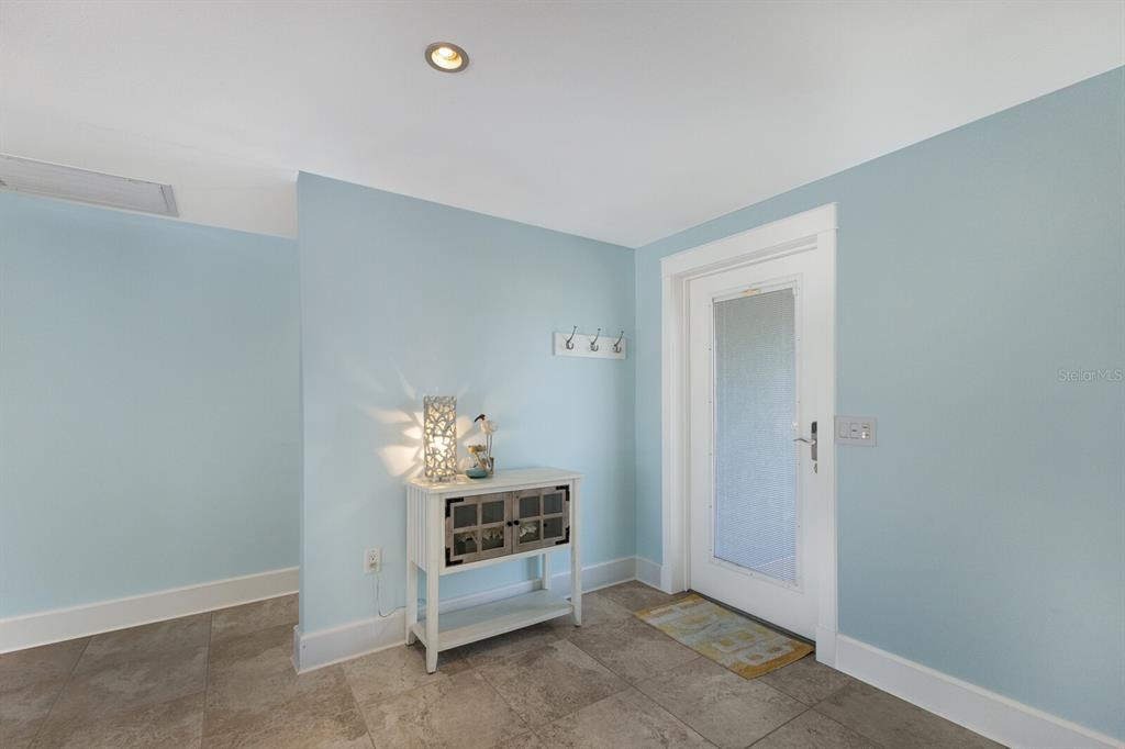 An entryway features light blue walls, tile flooring, a white console table, and a glass door — 506 69TH STREET, HOLMES BEACH, FL