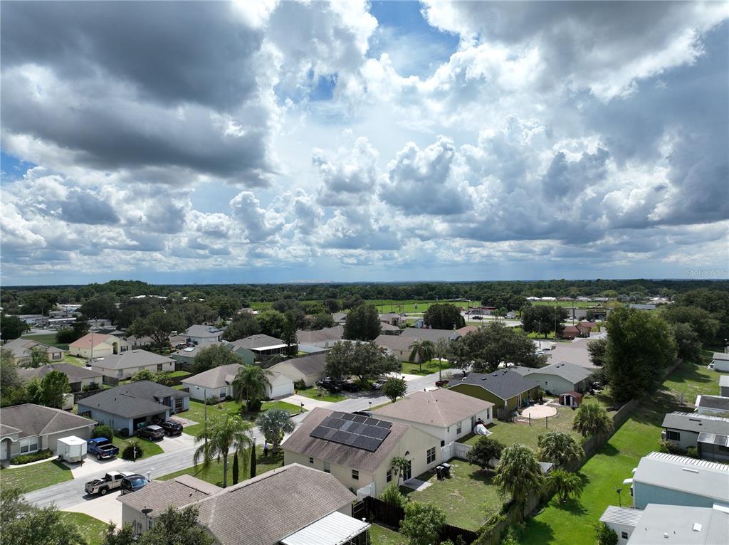 An aerial view shows a suburban neighborhood with houses, driveways, and a cloudy sky — 123 OSPREY HEIGHTS DRIVE, WINTER HAVEN, FL