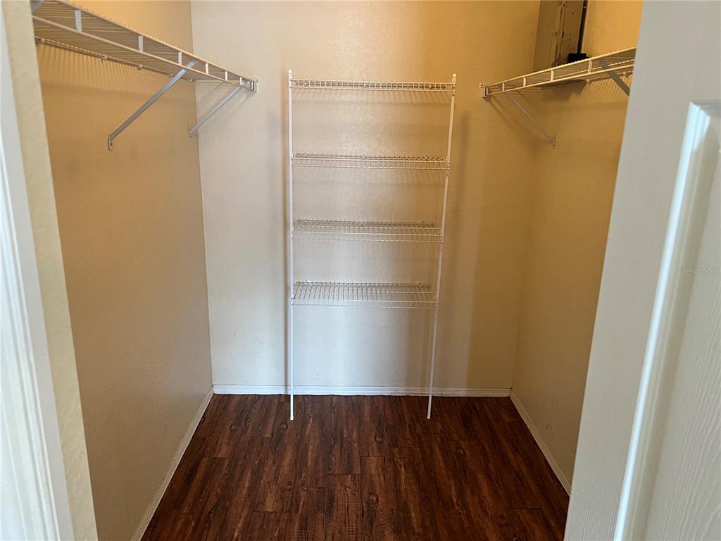 A walk-in closet features wire shelving, beige walls, and wood-look flooring — 123 OSPREY HEIGHTS DRIVE, WINTER HAVEN, FL