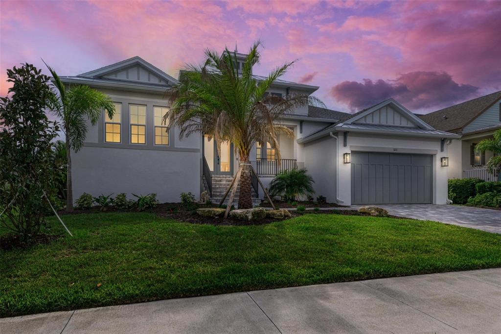 A modern two-story house features a gray garage, a palm tree, and a front entrance — 8211 37TH AVENUE CIRCLE W, BRADENTON, FL