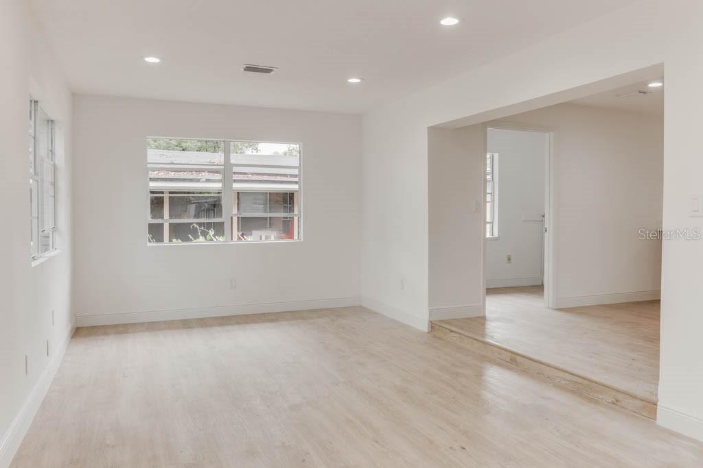 A bright, empty living room features light wood-look flooring, white walls, and a recessed entryway — 1255 PINE STREET, ALTAMONTE SPRINGS, FL