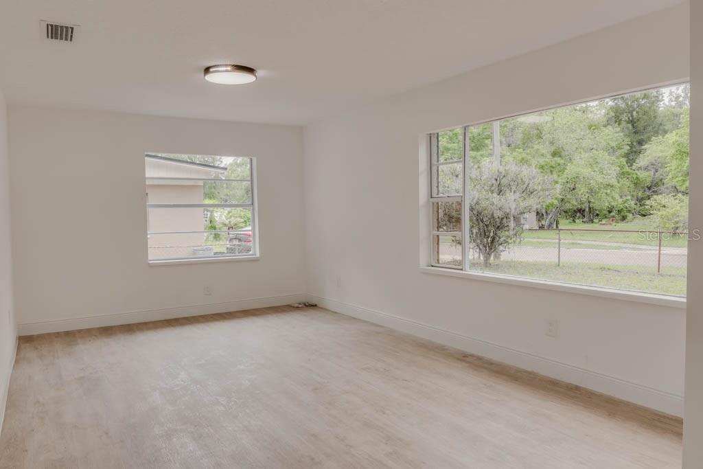 An empty room with white walls, light wood-look flooring, and two large windows — 1255 PINE STREET, ALTAMONTE SPRINGS, FL