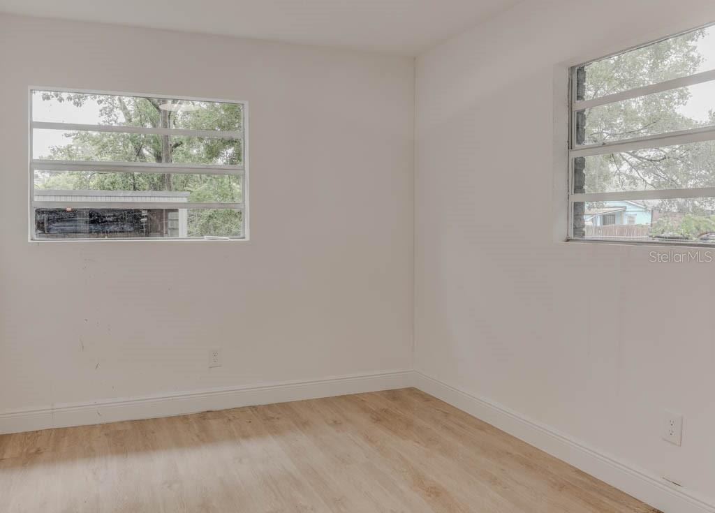 An empty room with white walls, light wood-look flooring, and two windows with metal frames — 1255 PINE STREET, ALTAMONTE SPRINGS, FL