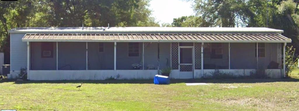 A single-story manufactured home features a full-length screened-in front porch and a metal roof — 6014 SE 86TH BOULEVARD UNIT 1, OKEECHOBEE, FL