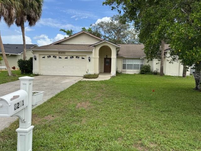 A single-story house with a beige exterior, a two-car garage, and a front lawn — 8201 RHANBUOY ROAD, SPRING HILL, FL