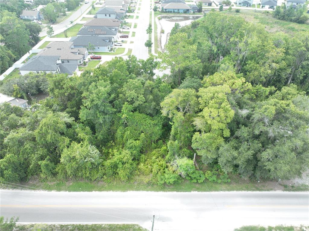 An aerial view shows a wooded vacant lot situated between a residential street and road — Lot 50, 51, 52 LAKE DR, NEW PORT RICHEY, FL