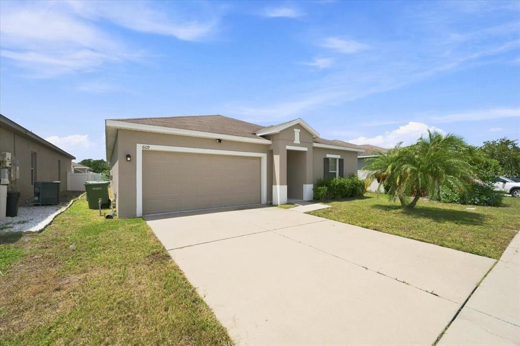 A single-story house with a beige exterior, a two-car garage, and a concrete driveway — 609 LUCERNE BOULEVARD, WINTER HAVEN, FL