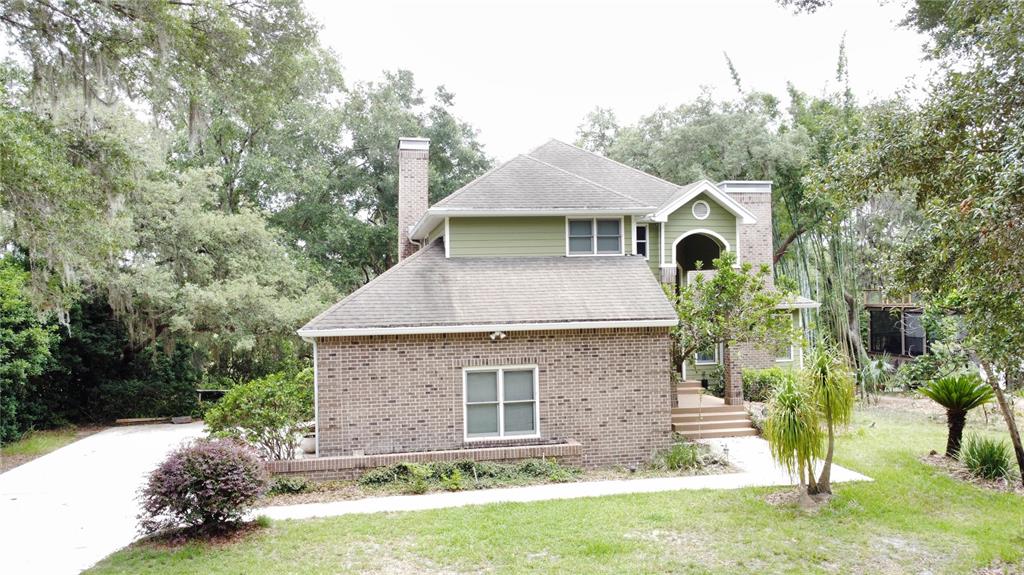 A two-story house with a brick lower level, green siding, and a shingled roof — 1016 LAKESIDE DR. DRIVE, APOPKA, FL