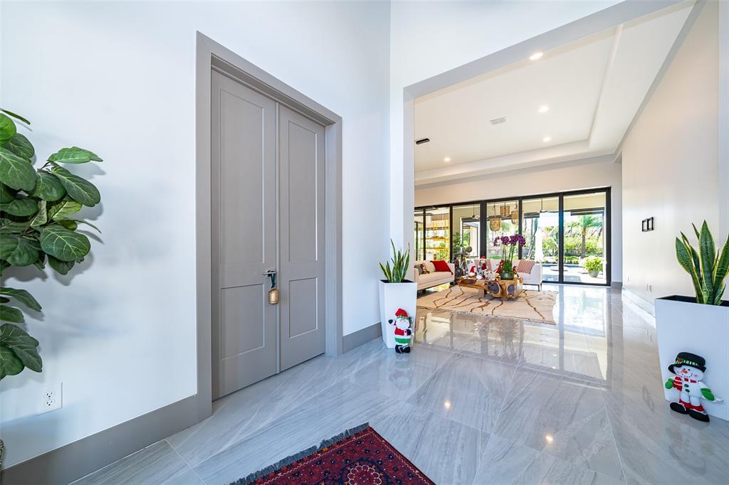 A bright foyer features gray double doors, glossy tile floors, and two decorative snowman planters — 15144 PENDIO DRIVE, BELLA COLLINA, FL